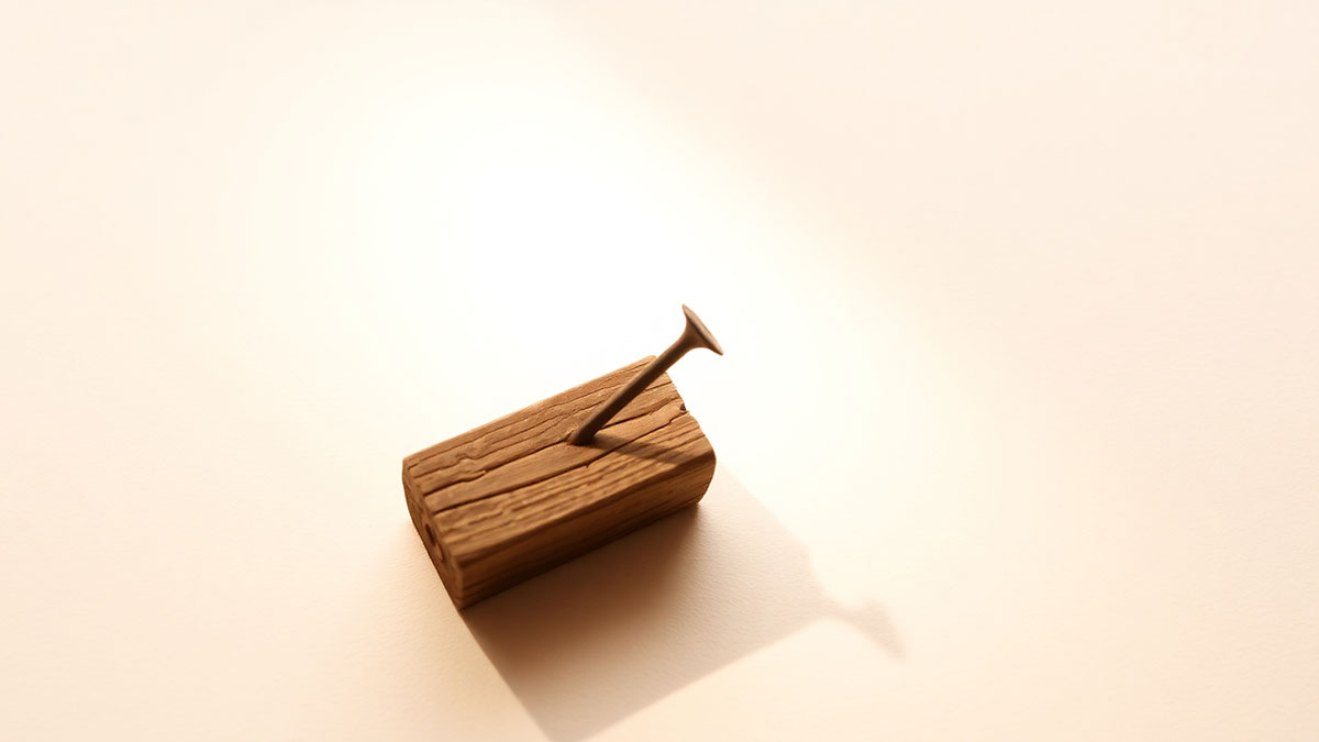 Nail on wood in soft light, representing sins nailed to the cross and hopeful victory through Bible verses like Colossians 2.