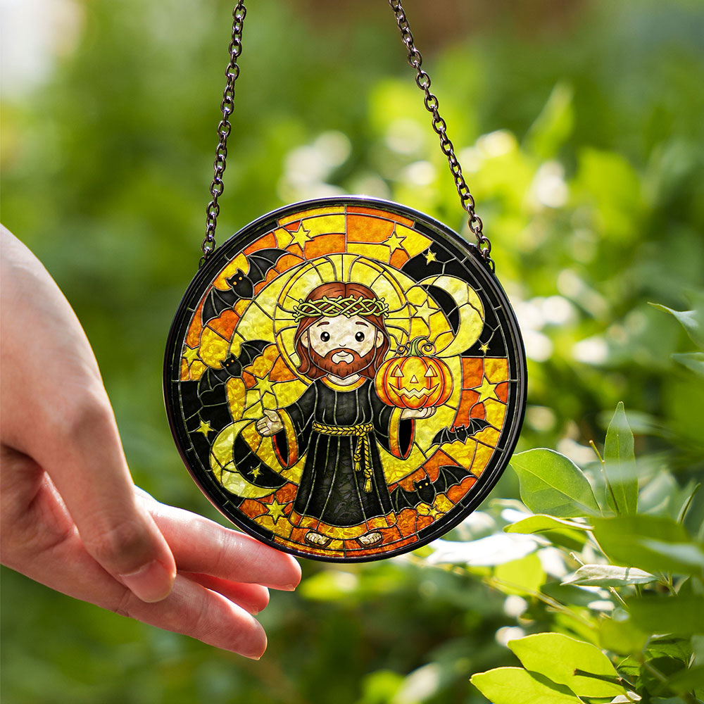 Hand holding Cute Jesus with Jack-o'-Lantern stained glass suncatcher outside, Christian Halloween decor for fall window or garden display.