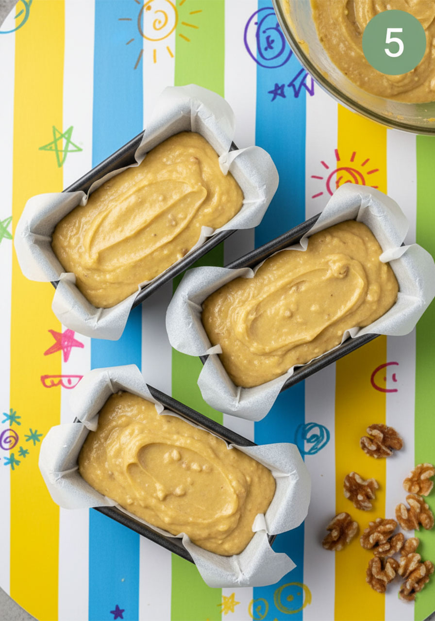 Vegan banana walnut bread batter poured into three parchment-lined mini loaf pans ready to bake step 5